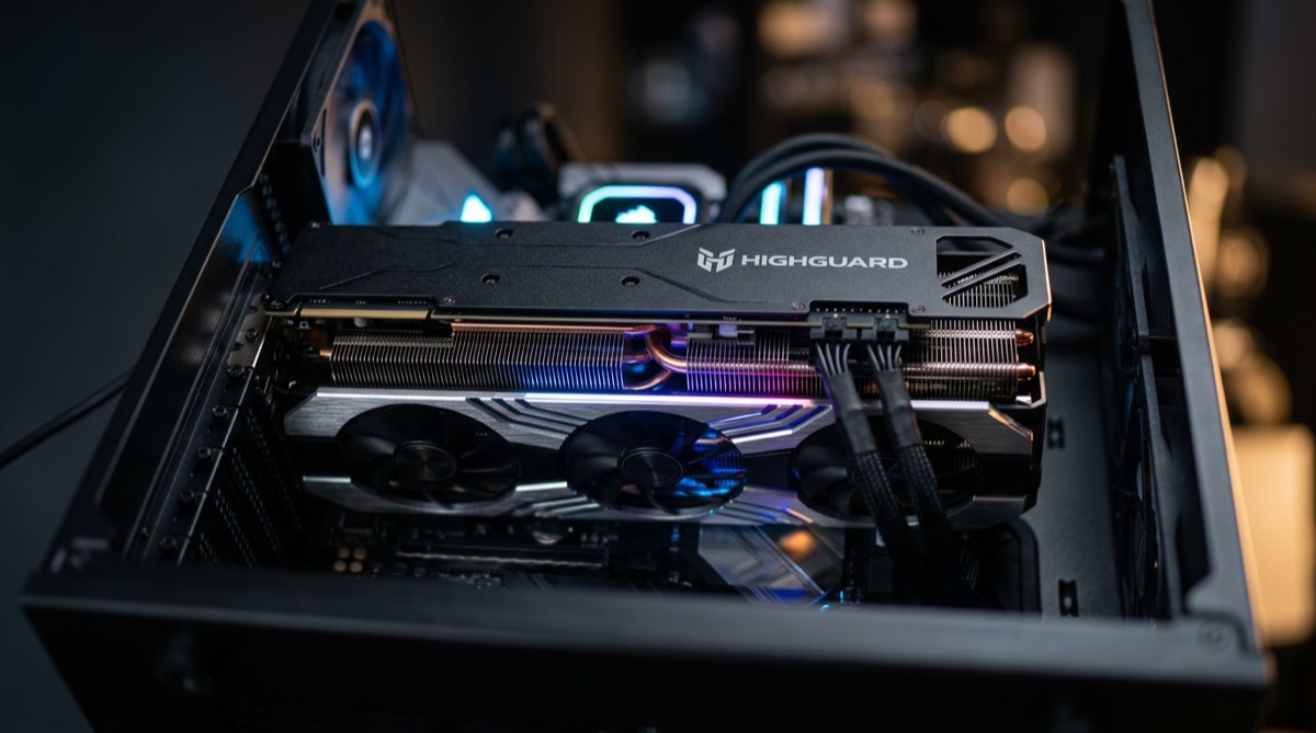 A close-up shot of a high-end graphics card, glowing with RGB lighting inside a PC case. The Highguard logo is subtly reflected on the card's backplate.